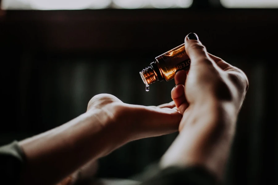 Les mains d'une femme versant du liquide d'une bouteille de cosmétiques