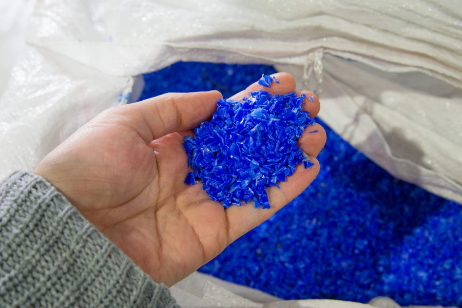 砕いたプラスチックのペレットを持つ作業員