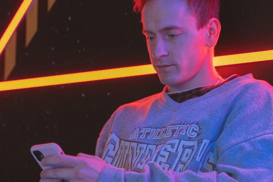 Young man using phone while wearing a collegiate sweatshirt