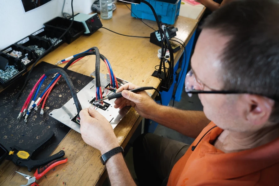 Un hombre que suelda el mazo de cables para scooter eléctrico