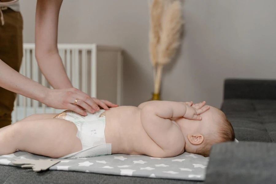 Una mamma che cambia il pannolino al suo bambino