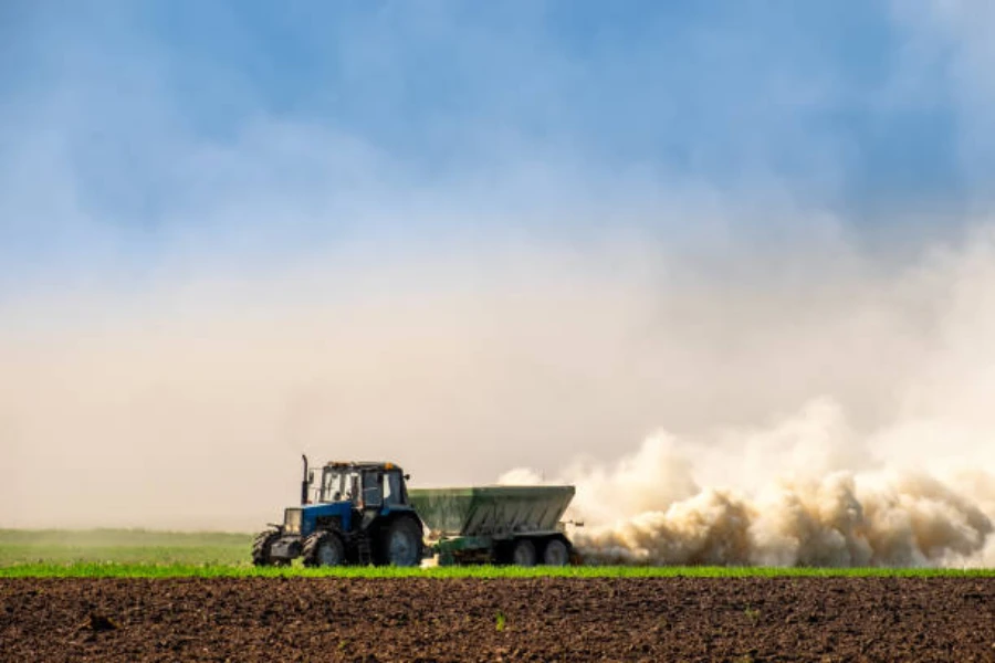 A tractor spraying fertilizer on soil