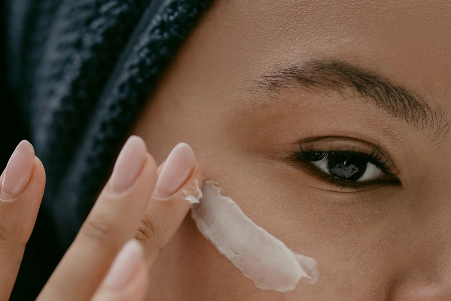 A woman applying white sunscreen to her face