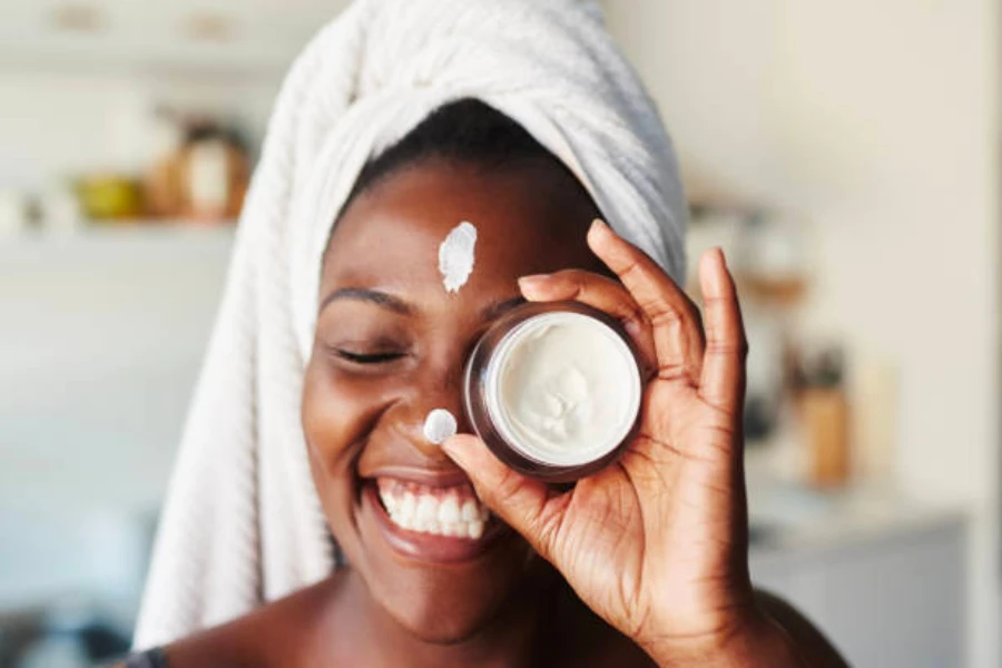 A woman holding a jar of sunscreen up to her face