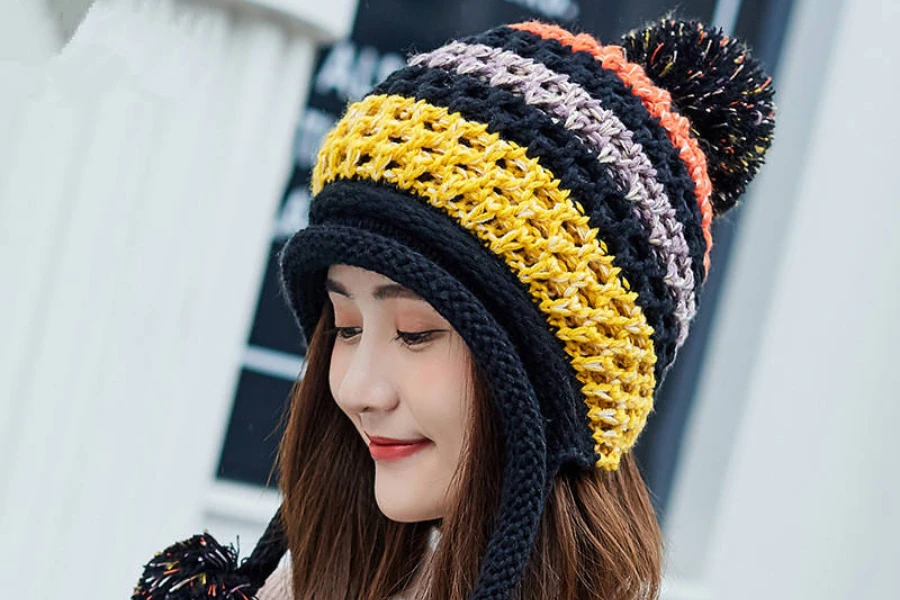 Seorang wanita mengenakan beanie penutup telinga rajut dengan pom pom