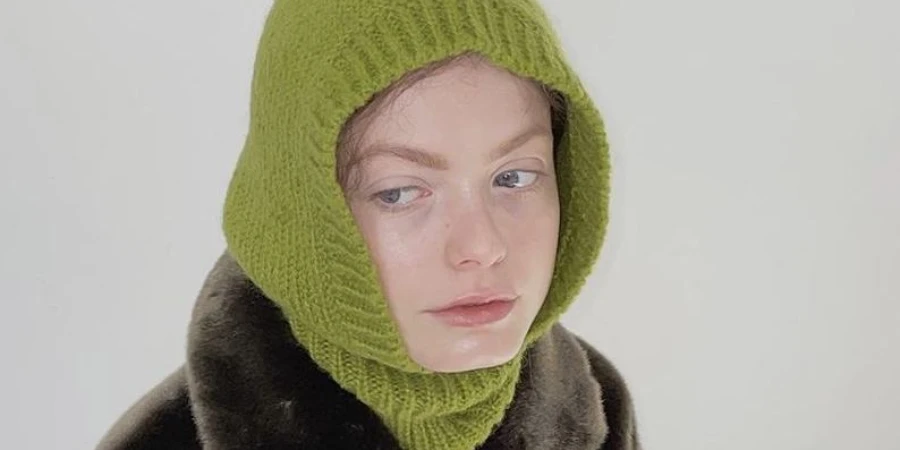 A woman wearing a light green knit hood balaclava