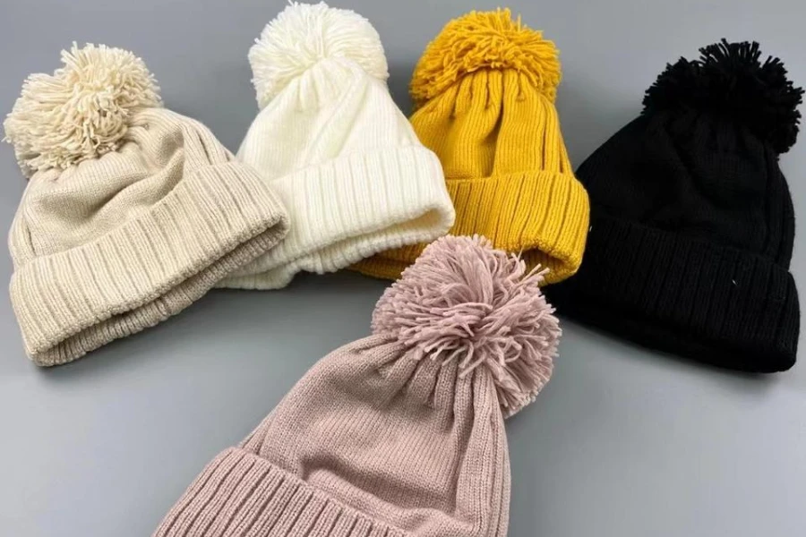 Collection of pink, black, beige, and yellow pom-pom beanies