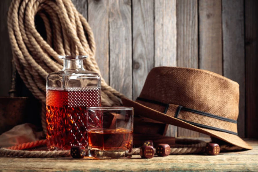 Sombrero de ala ancha de cáñamo junto a un vaso de whisky