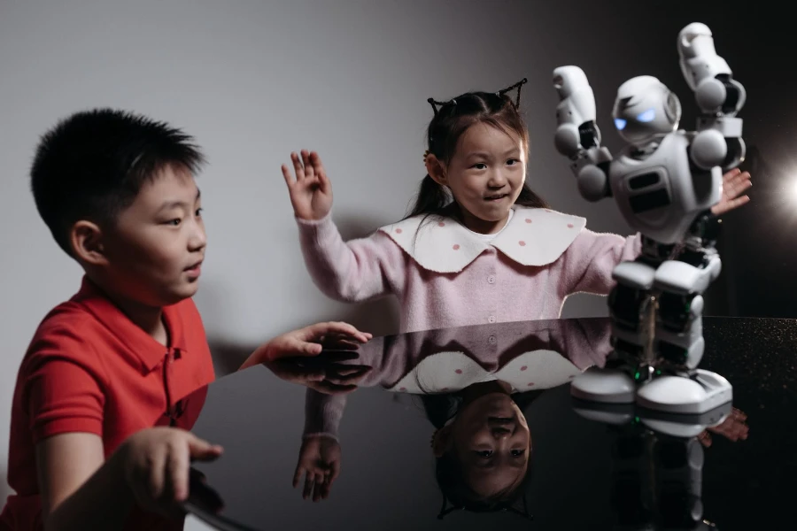 Niños mirando robot de juguete blanco bailando sobre la mesa