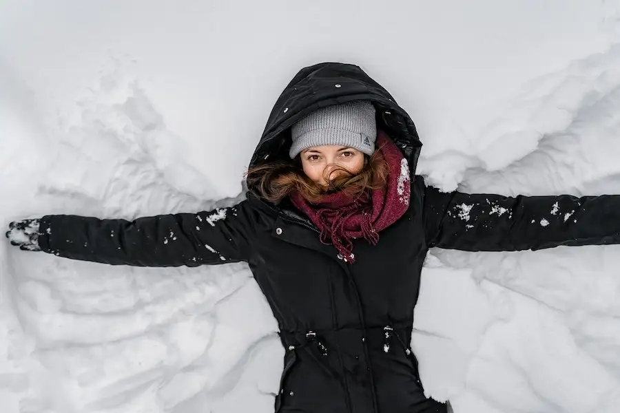 Lady in a black shell jacket making a snow angel