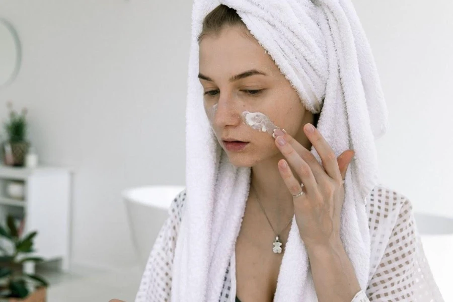 Lady wearing a head towel and applying skin finish