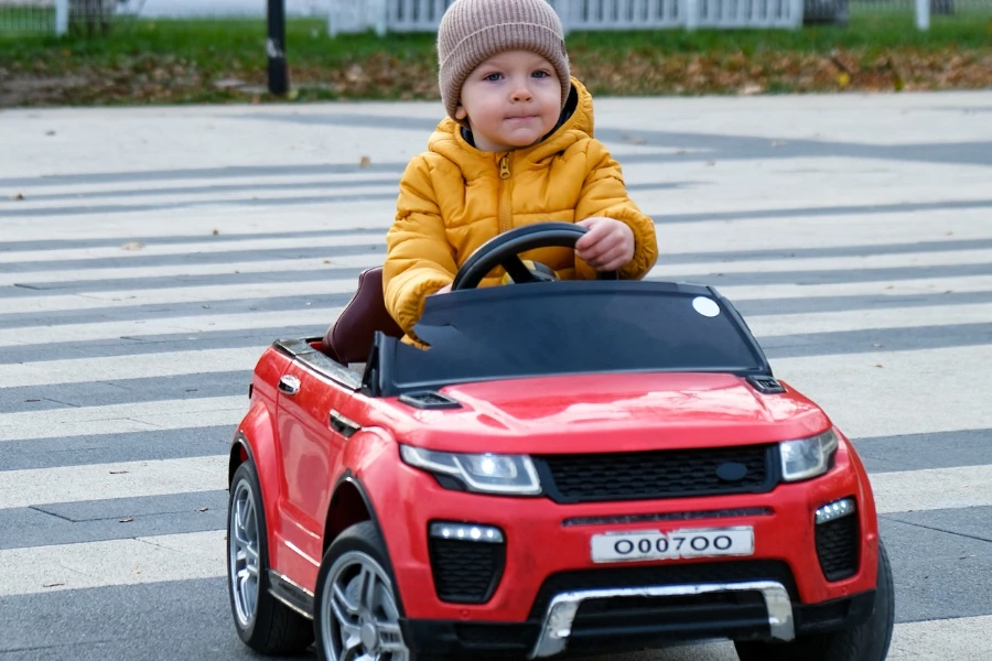 Kleiner Junge fährt ein rotes Spielzeugauto