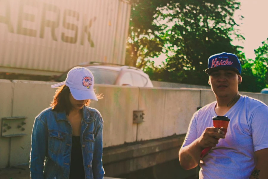 Man and woman wearing baseball caps outside