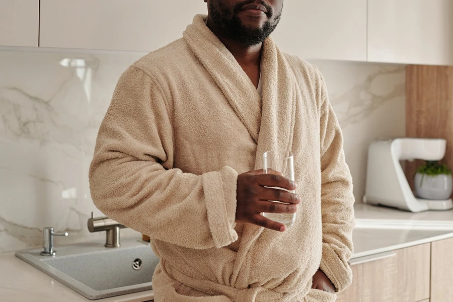 Man holding a glass cup wearing an Après-ski robe