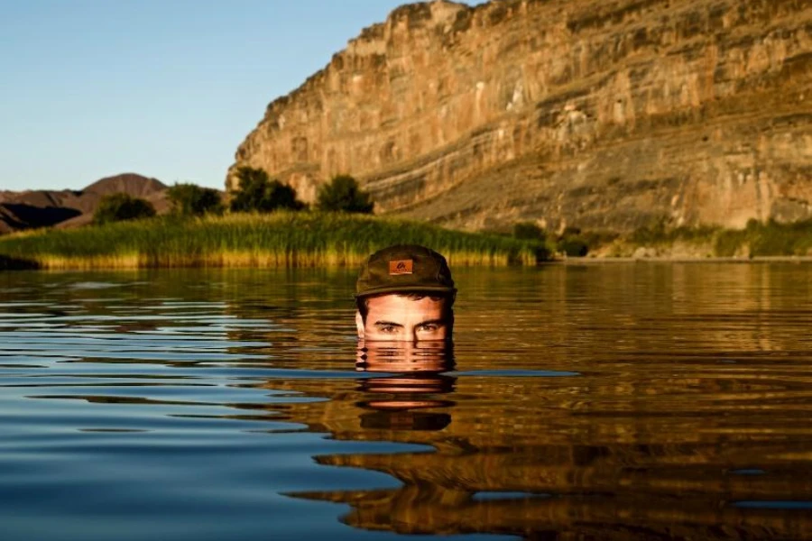 Man in water wearing camp hat with leather patch