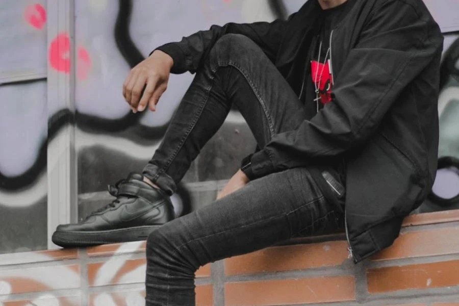 Man sitting on a fence while wearing black skinny jeans