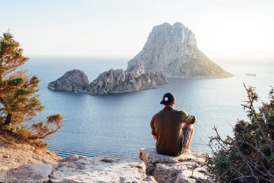 Man standing on cliff looking out at water