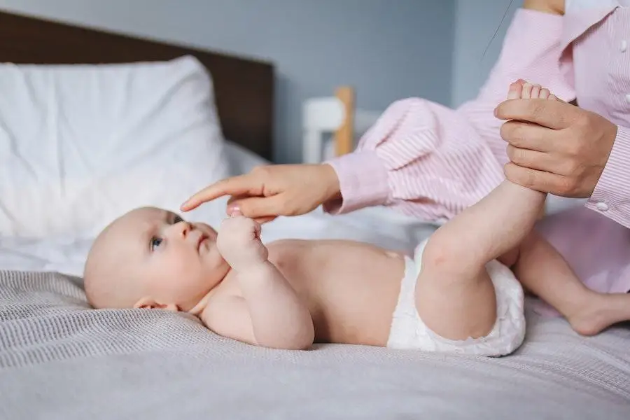 Mãe brincando com seu bebê usando uma fralda branca