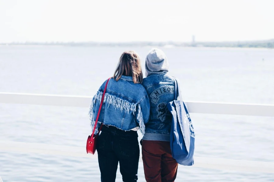 People wearing denim jackets staring at an ocean