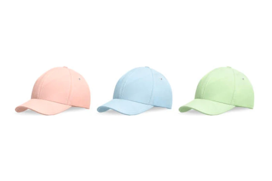 Three baseball caps in the colors pink, blue, and green