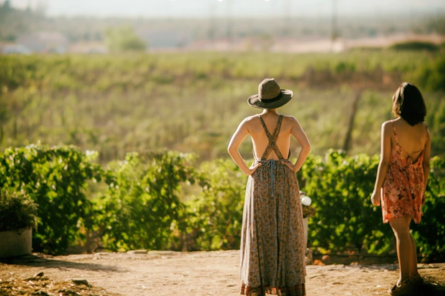 Two women wearing floral pleated dresses while out in nature