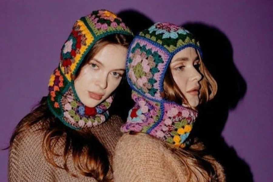 Two women wearing multi-color crochet granny square balaclavas