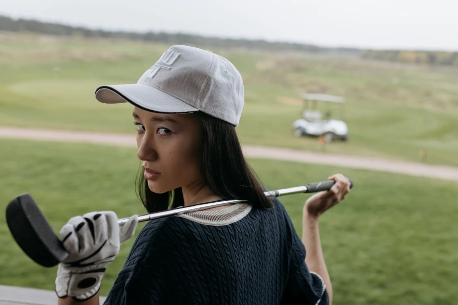 Wanita bermain golf dengan topi bisbol yang pas