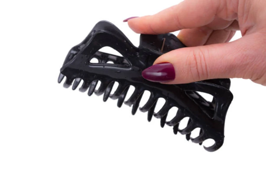 Woman holding a large black hair claw clip in air