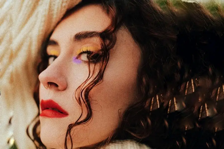 Woman in bold, colorful eye makeup and red lipstick