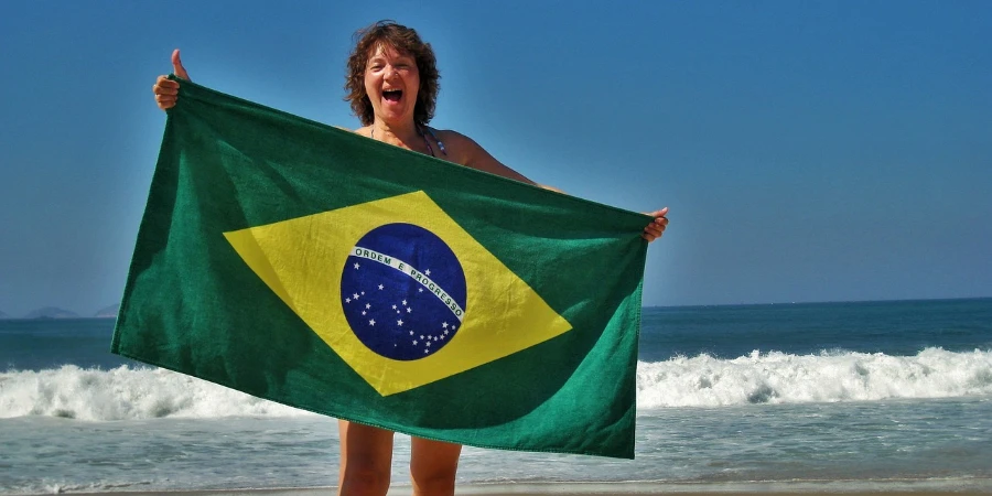 Woman on the beach holding a Brazilian flag