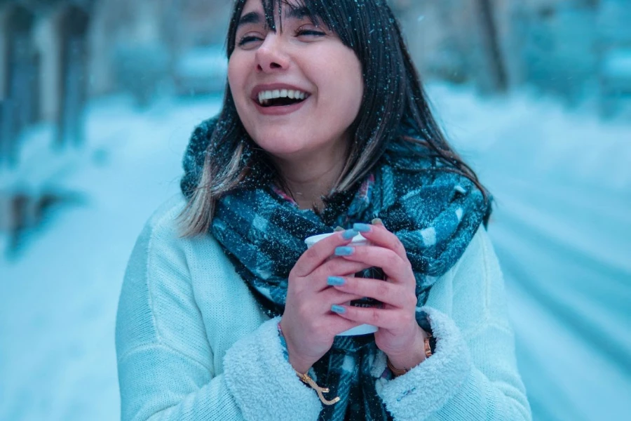 Woman posing in the snow with a knit scarf