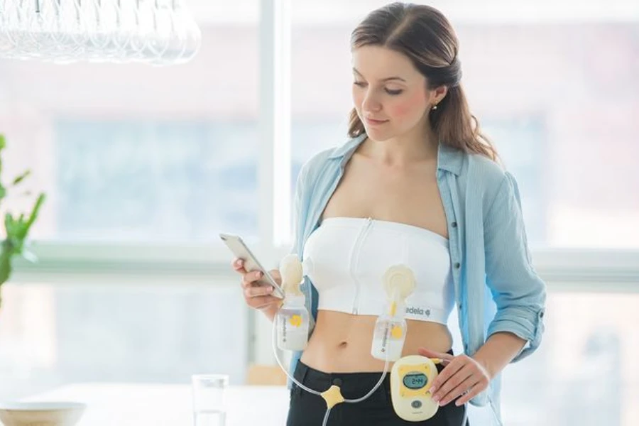 Woman pressing her phone while pumping breast milk