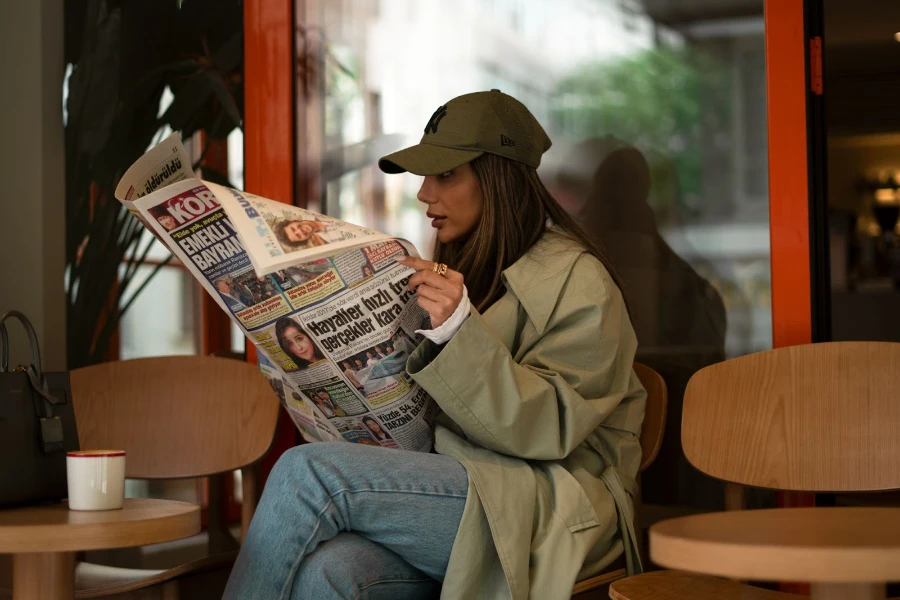 Woman reading a newspaper wearing a waterproof cap