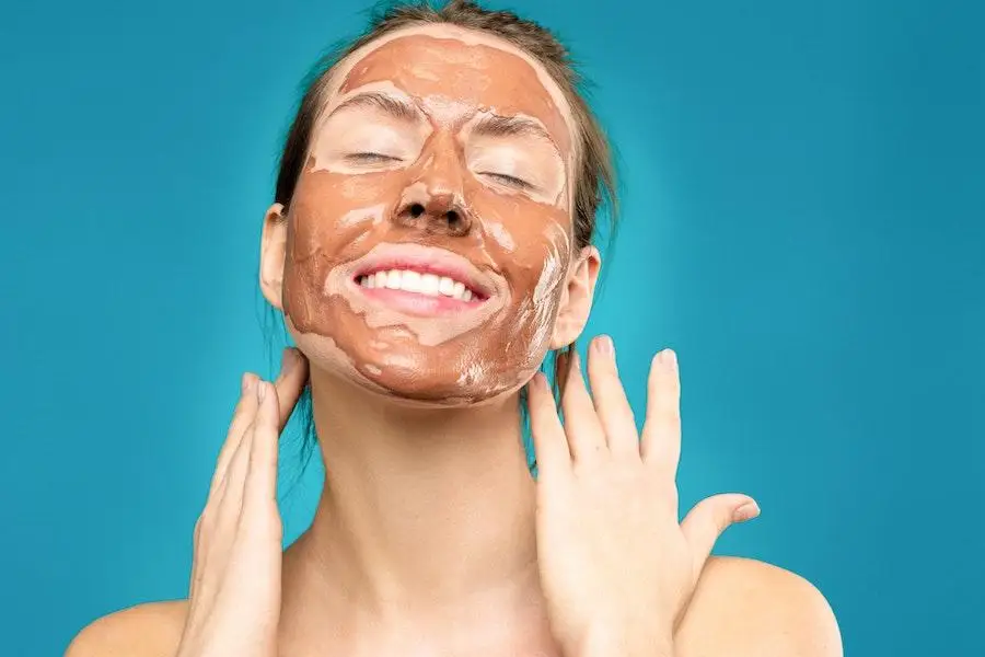 Woman smiling with brown skin finish applied on her face