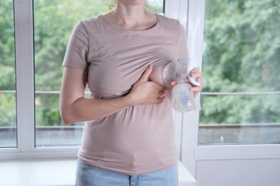 Woman using a wireless portable electric pump while holding breasts