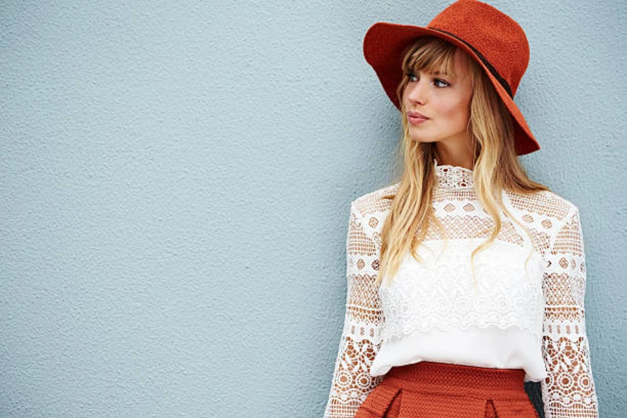 Woman wearing red floppy hat against a light blue wall