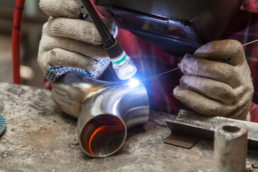 Young welder welding a y-shaped pipe