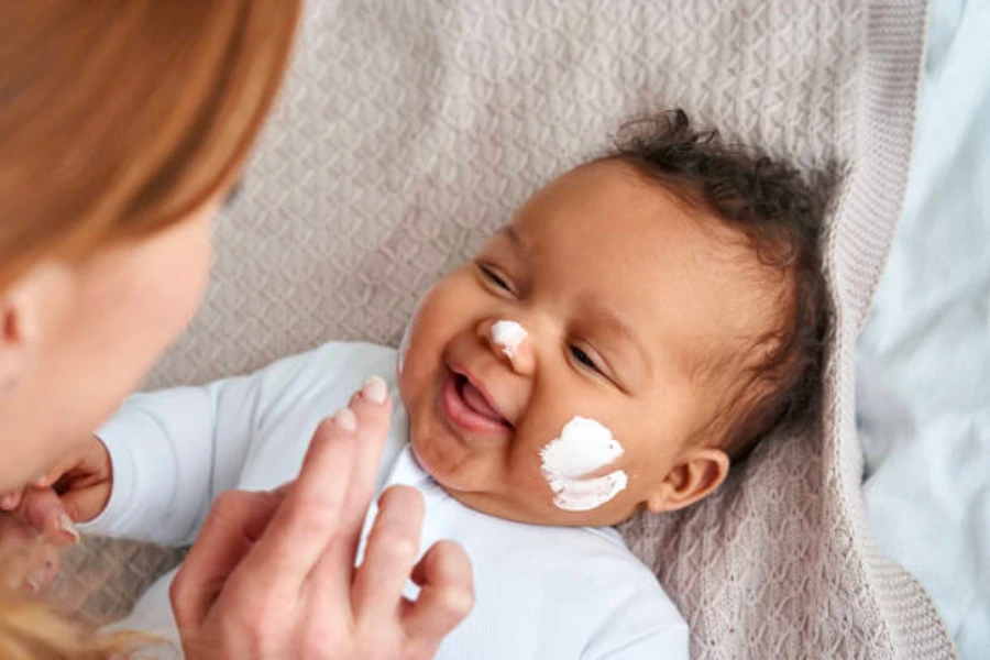 Ein Baby liegt da und erhält Hautpflege für sein Gesicht