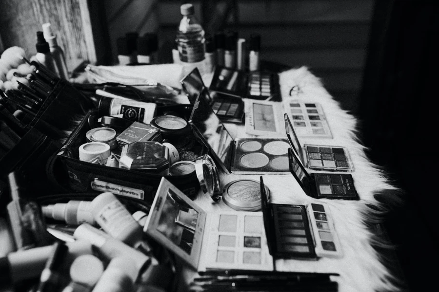 A black and white photo of makeup on a table with a white fur cover