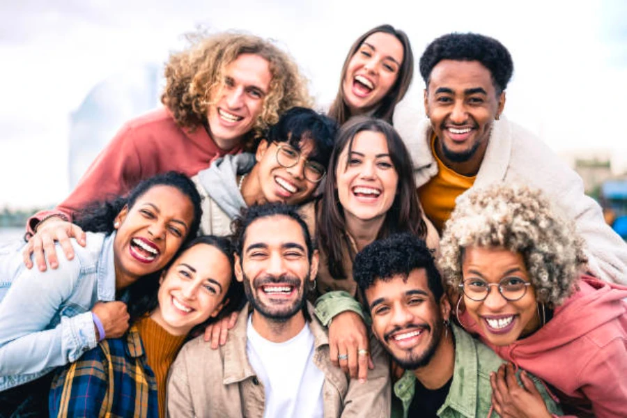 Un gruppo eterogeneo di persone che si abbracciano e sorridono