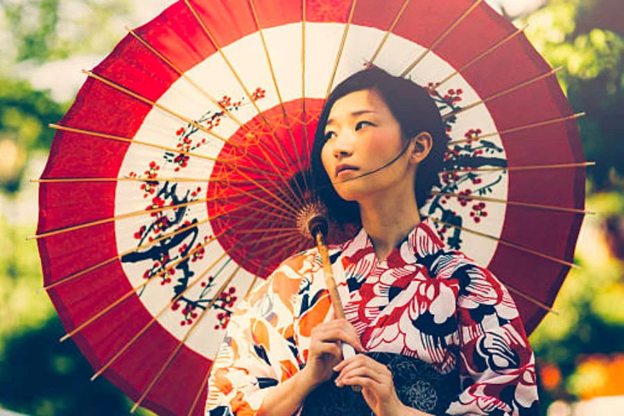 Uma mulher japonesa vestindo roupas tradicionais segurando um guarda-chuva