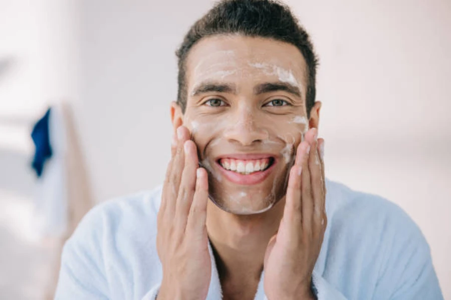 A man smiling and applying facecream with his hands