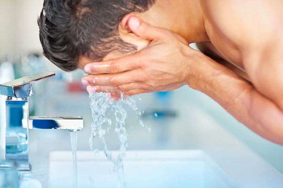 Ein Mann wäscht sein Gesicht im Badezimmerwaschbecken