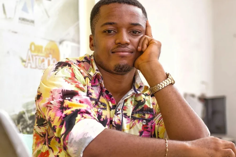A man wearing a floral patterned shirt and a gold wristwatch