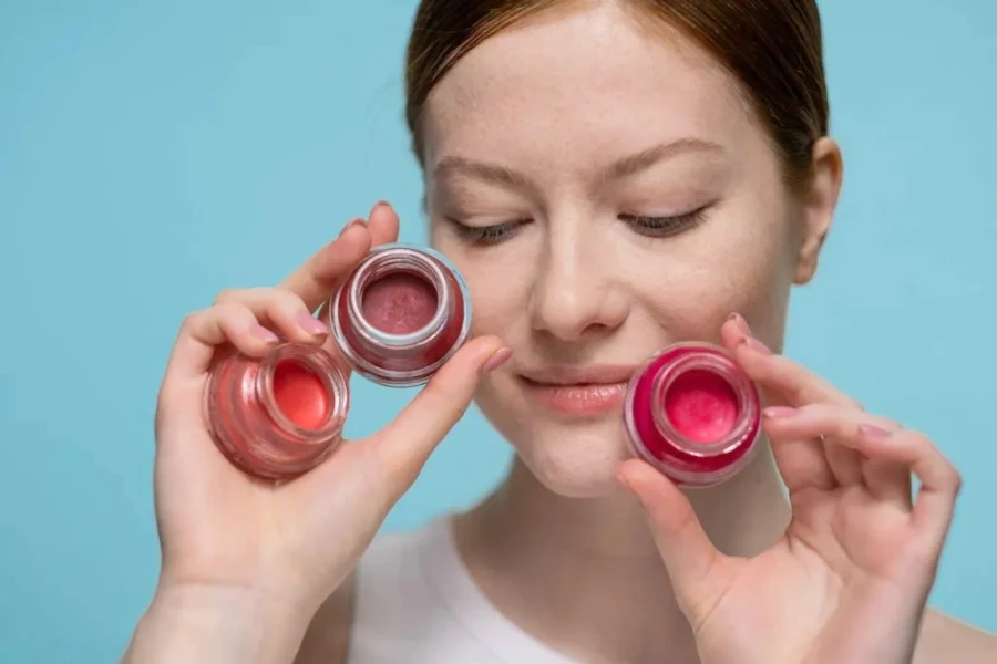 A woman holding a strawberry-colored beauty cream