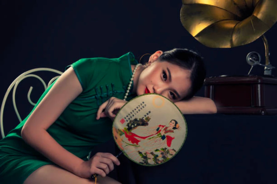 A woman laying her head down on a desk with a woven fan