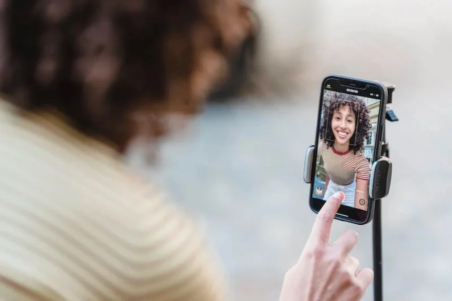 Eine Frau blickt auf ihrem Handy in die Kamera