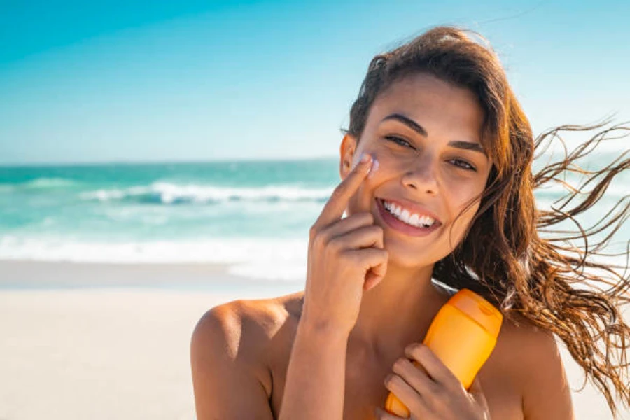 A woman on the beach applying sun care