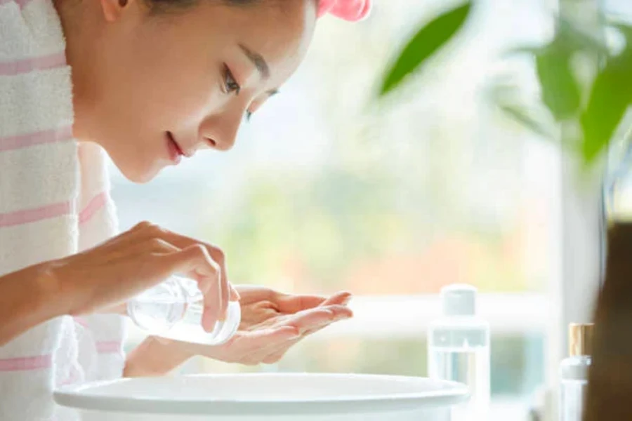 A woman pouring a facial serum in her hands to apply to her face