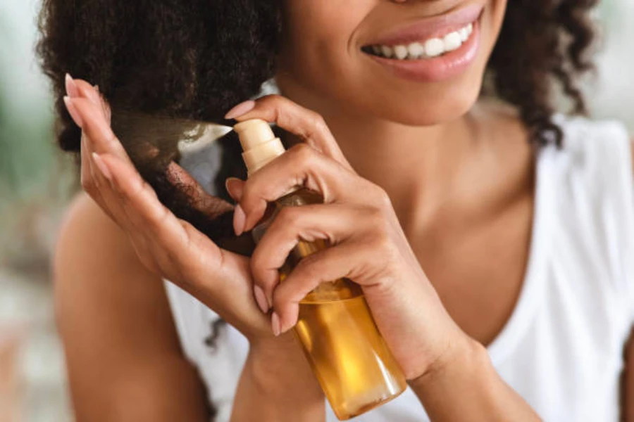 A woman spraying her naturally curly hair with hair care oil